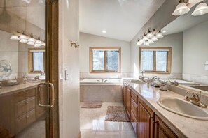 A modern bathroom with a walk-in shower, a large bathtub, and a double vanity with a large mirror. - Streamside 333B (Frisco)