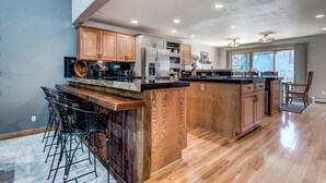 A spacious kitchen with wooden cabinets, a central island, and bar stools. - Streamside 333B (Frisco)