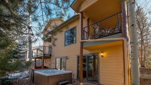 A two-story house with a hot tub, a balcony with outdoor furniture, and a wooden deck. - Streamside 333B (Frisco)
