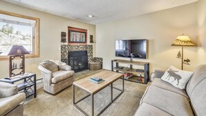 A cozy living room with a fireplace, a television, and comfortable seating. - Forest Park F (Frisco)