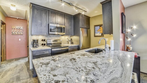 A modern kitchen with granite countertops, stainless steel appliances, and a central island. - Forest Park F (Frisco)