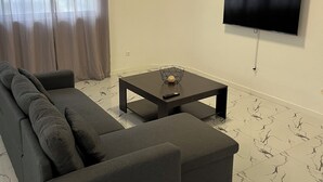 Una sala de estar moderna con un sofá modular, una mesa de centro y un televisor de pantalla plana montado en la pared.