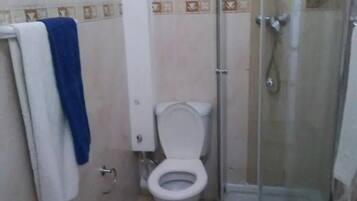 A bathroom with a toilet, a shower enclosure, and a towel rack.