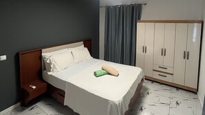 Un dormitorio con cama, armario, mesita de noche y una lámpara en el techo.