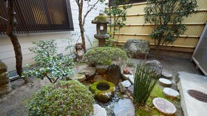 A traditional Japanese garden with a stone lantern, moss-covered rocks, and a small pond. - Miyazakiya (Kyoto)
