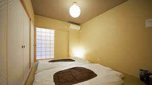 A hotel room with two beds, a sliding door, an air conditioning unit, and a light fixture. - Miyazakiya (Kyoto)