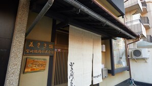 A building with a traditional Japanese entrance, a wooden signboard, and a hanging paper with Japanese characters. - Miyazakiya (Kyoto)