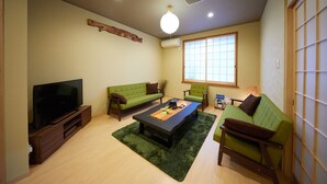 A living room with a flat-screen TV, two green sofas, a coffee table, and a large window. - Miyazakiya (Kyoto)