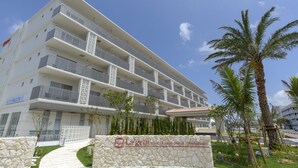 A multi-story hotel with a stone facade, balconies, and a sign indicating it is the "Lagent Hotel Okinawa Shibara Hotel & Resort". - La'gent Hotel Okinawa Chatan - Hostel (Chatan)