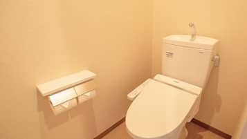 Un baño moderno y funcional con un inodoro blanco, un dispensador de papel higiénico y tanque de inodoro TOTO.
