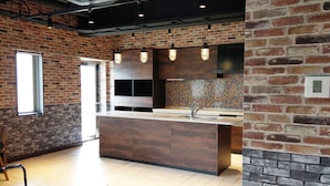 A modern kitchen with exposed brick walls, pendant lighting, and a central island with a sink. - La'gent Hotel Okinawa Chatan - Hostel (Chatan)