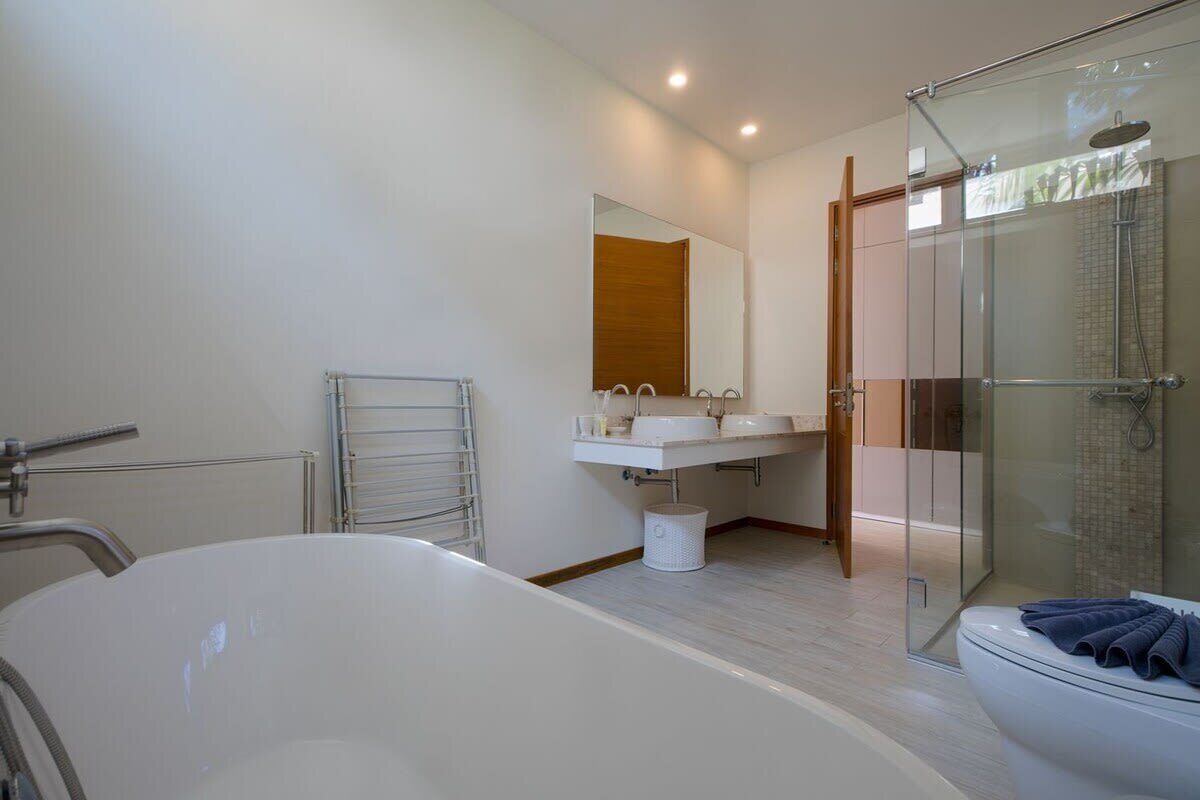 A modern bathroom with a large bathtub, a glass-enclosed shower, and a wooden door.