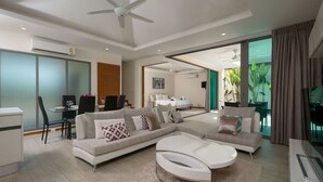 Uma sala de estar moderna com um sofá seccional, uma mesa de centro branca e um espaço de jantar com mesa e cadeiras.