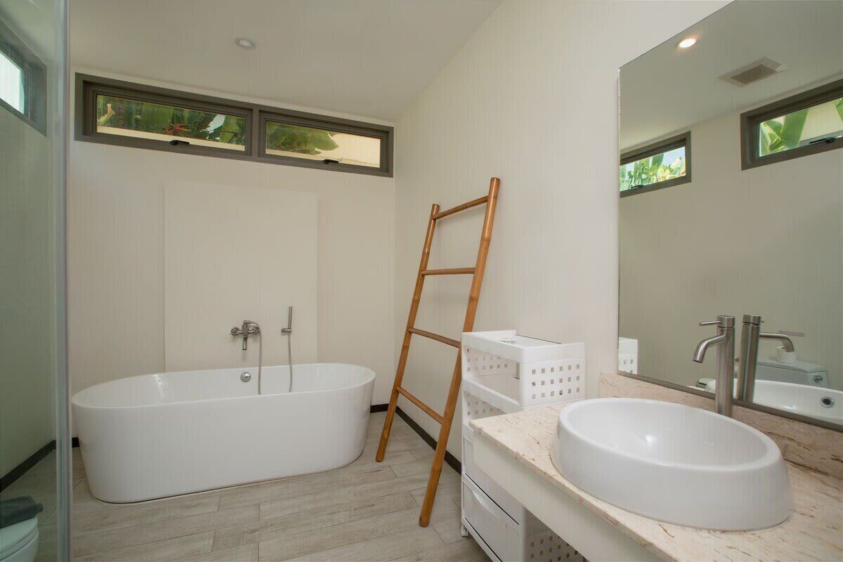 A modern bathroom with a freestanding bathtub, a vanity with a sink, and a large mirror.