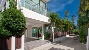 A modern two-story building with large windows, a balcony, and a paved driveway. - Laem Ka Residence by Tropiclook (Rawai)