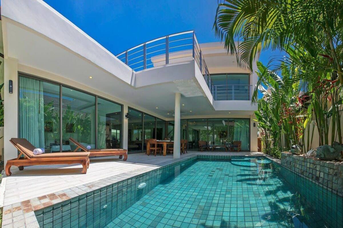 Une maison moderne dotée d’une piscine, d’un patio couvert et d’un balcon.