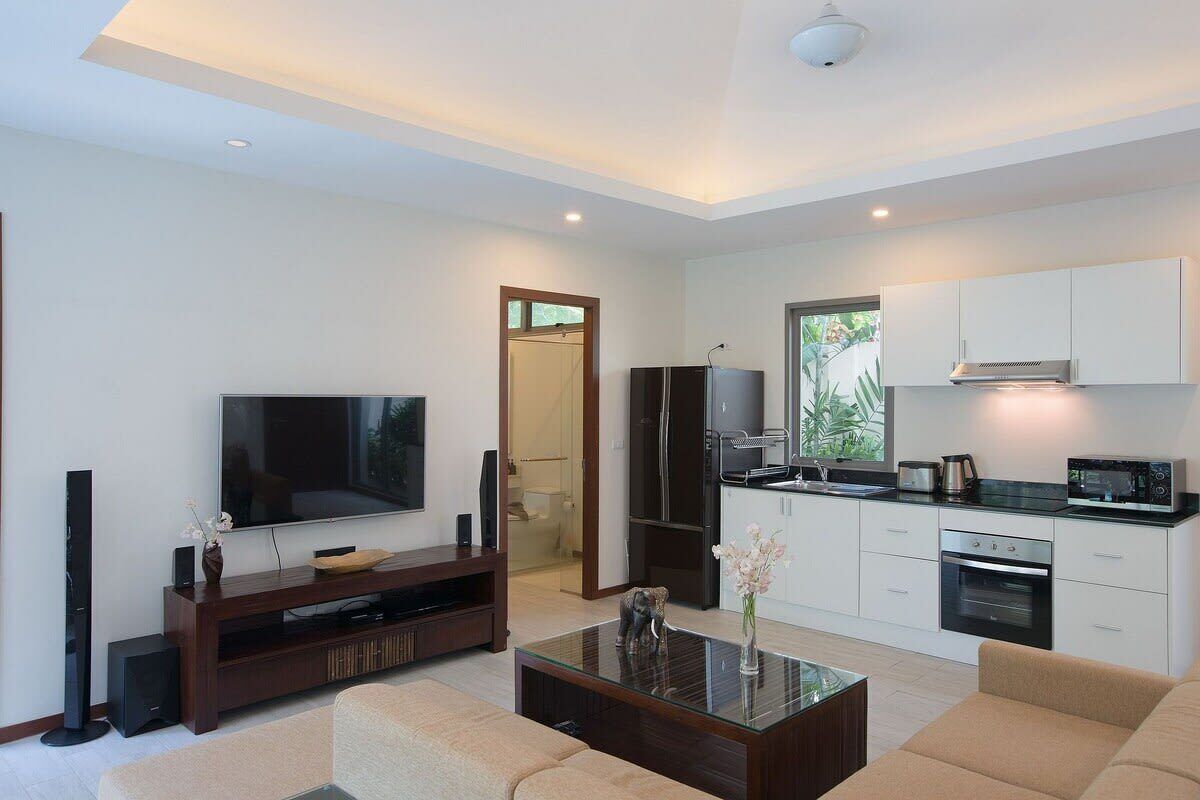 Een moderne woonkamer met een flatscreen televisie, een entertainmentmeubel van donker hout en een glazen salontafel.