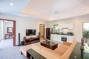 Un salon moderne comprenant un canapé, une table basse, un téléviseur et un coin cuisine.
