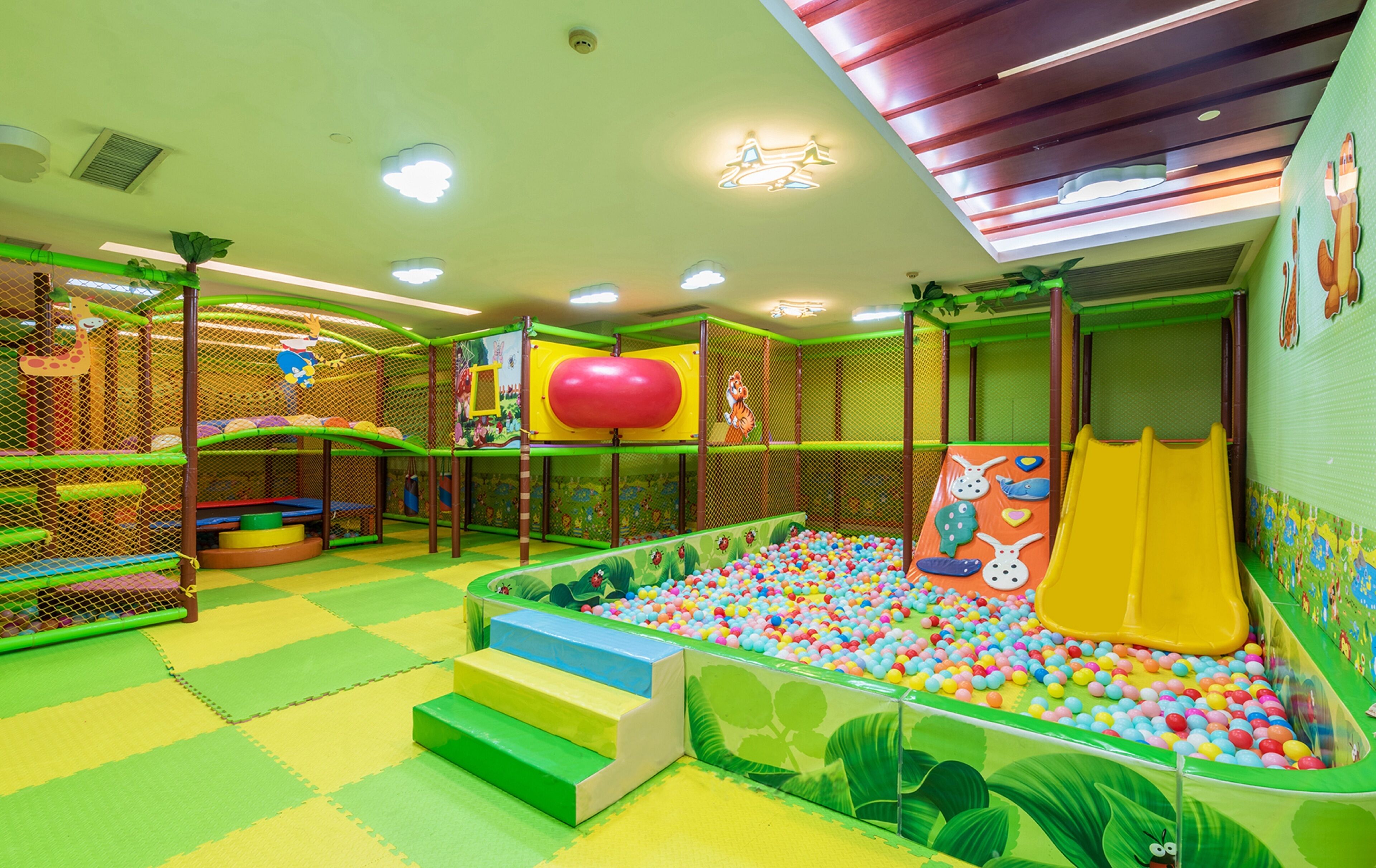 Zona de juegos infantiles con piscina de pelotas, toboganes y estructuras para escalar.