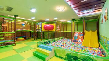 Zona de juegos infantiles con piscina de pelotas, toboganes y estructuras para escalar.