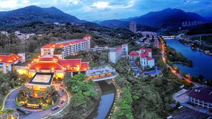 A hotel with multiple buildings, a central courtyard, and a river in the background. - C&D Hotel Putian (Putian)