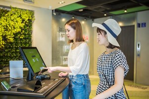Ein Empfangsbereich mit einem digitalen Kiosk, einer grünen Wand und einer Tür im Hintergrund.