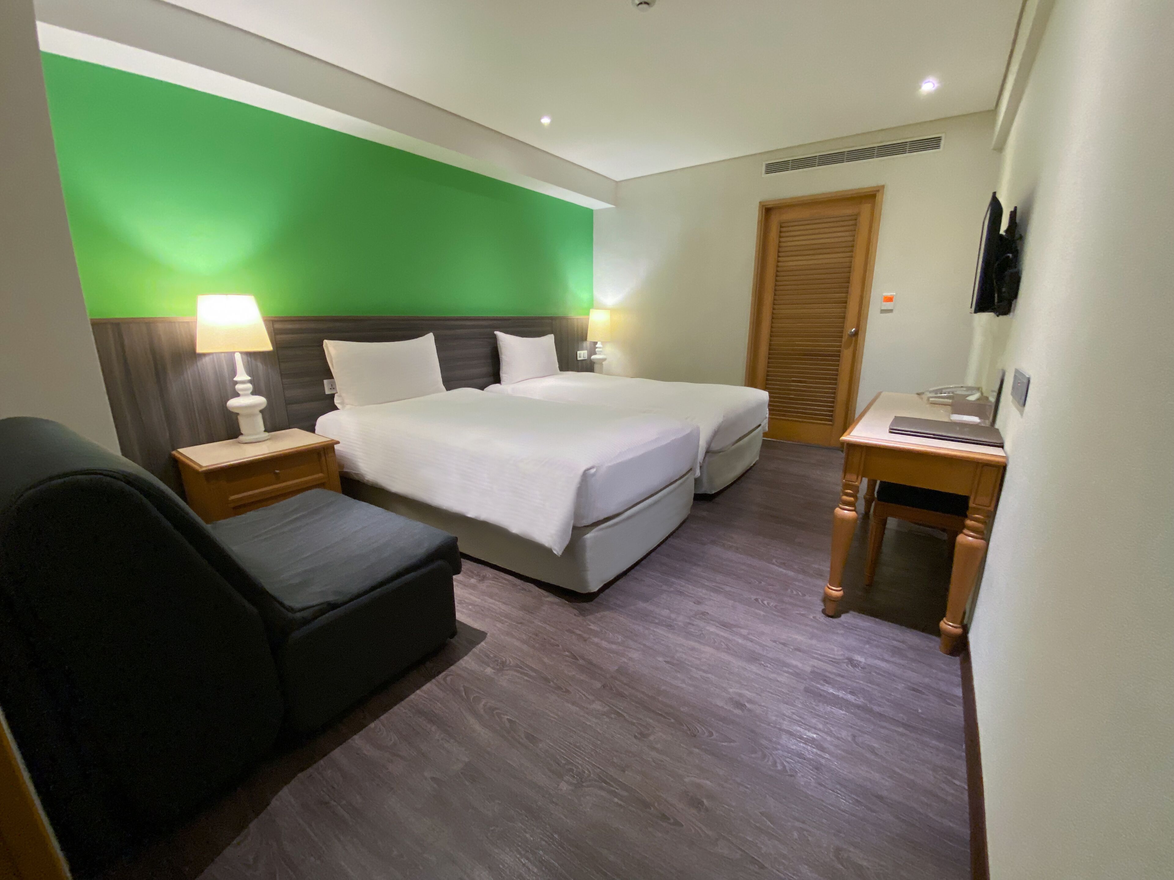 A hotel room with a bed, bedside tables, a desk, and a chair.