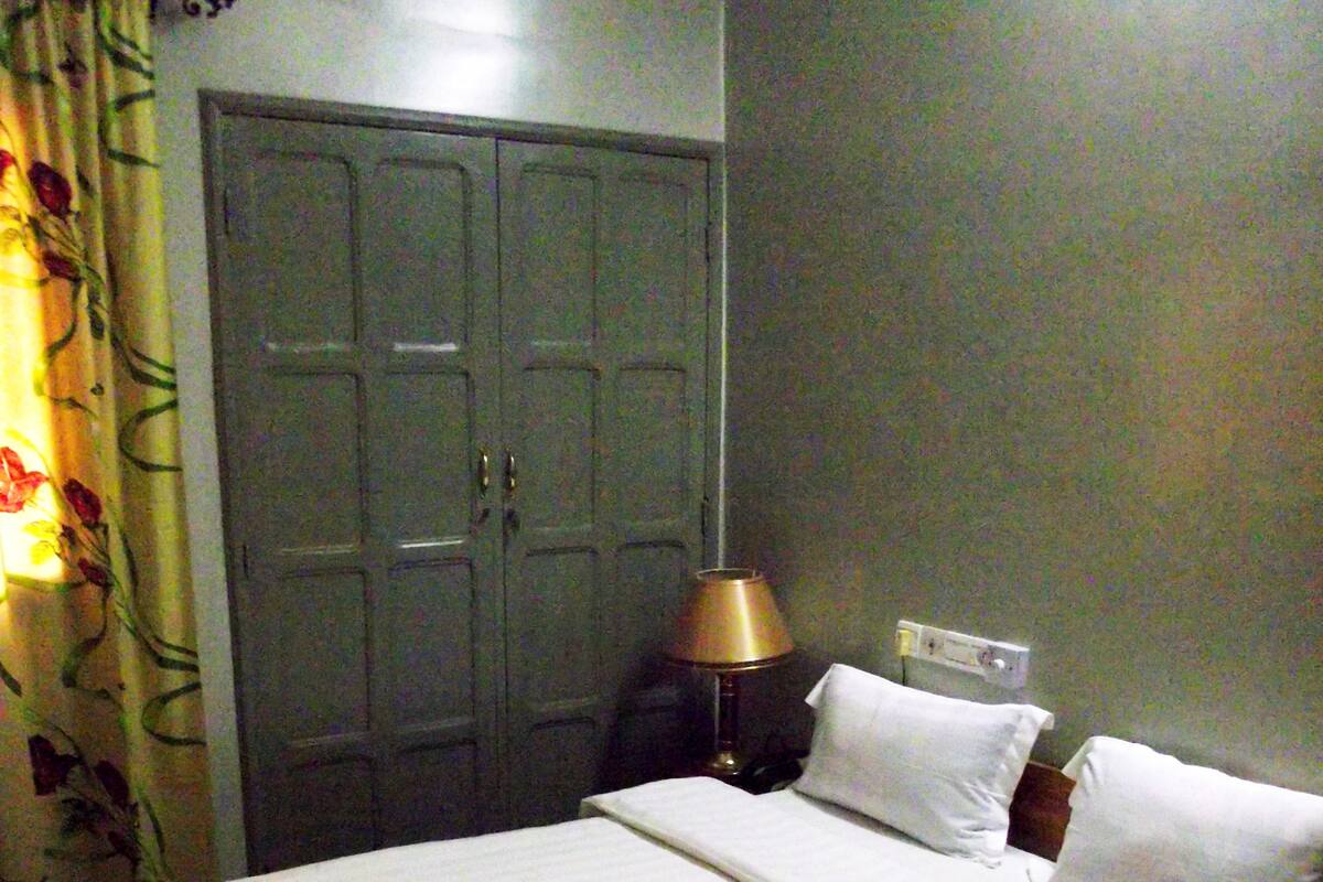 A standard hotel room with a bed, a nightstand, a lamp, and a wardrobe.