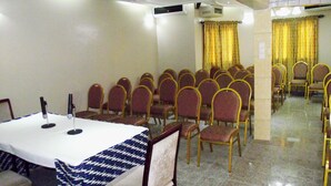 A conference room with a long table, rows of chairs, and a chandelier. - Hotel Magnificat Baguida (Lomé)