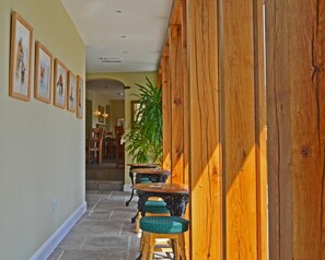 A hallway with framed pictures on the wall, wooden paneling on one side, and a staircase leading to another room. - The Drayton Crown (Langport)