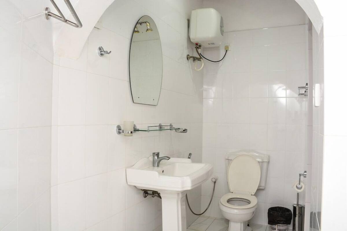 A bathroom with a white sink, toilet, and a mirror.
