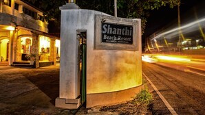 A sign for Shanthi Beach Resort with a clear view of the resort's entrance and a street in the background. - Shanthi beach resort (Unawatuna)