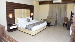 A modern hotel room with a large bed, a sofa, a desk, and a TV. - Moments (Lucknow)