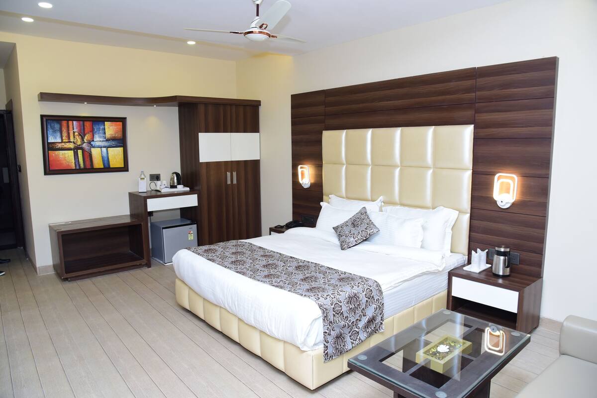 Una habitación de hotel moderna con una cama grande, mesitas de noche, un escritorio y un ventilador de techo.