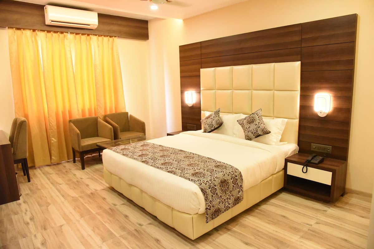 Una habitación de hotel con una cama grande, dos sillones, un escritorio y una mesita de noche con un teléfono.