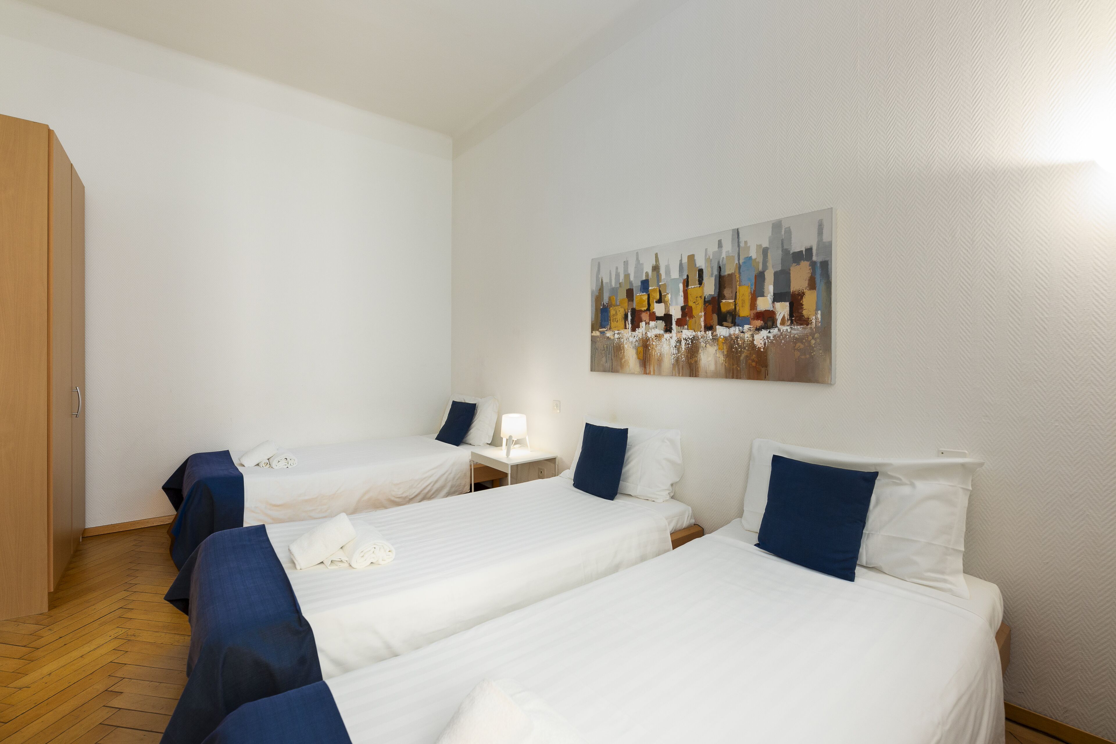 Ein Hotelzimmer mit zwei Einzelbetten, einem Holzschrank und einem Bild an der Wand.