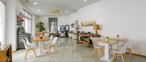 A modern dining area with white chairs, a wooden table, and a ceiling fan.