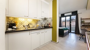 A modern kitchen with white cabinets and patterned backsplash, a dining area with a table and chairs, and a view of buildings through a large window. - Lugano Center GuestHouse (Lugano)