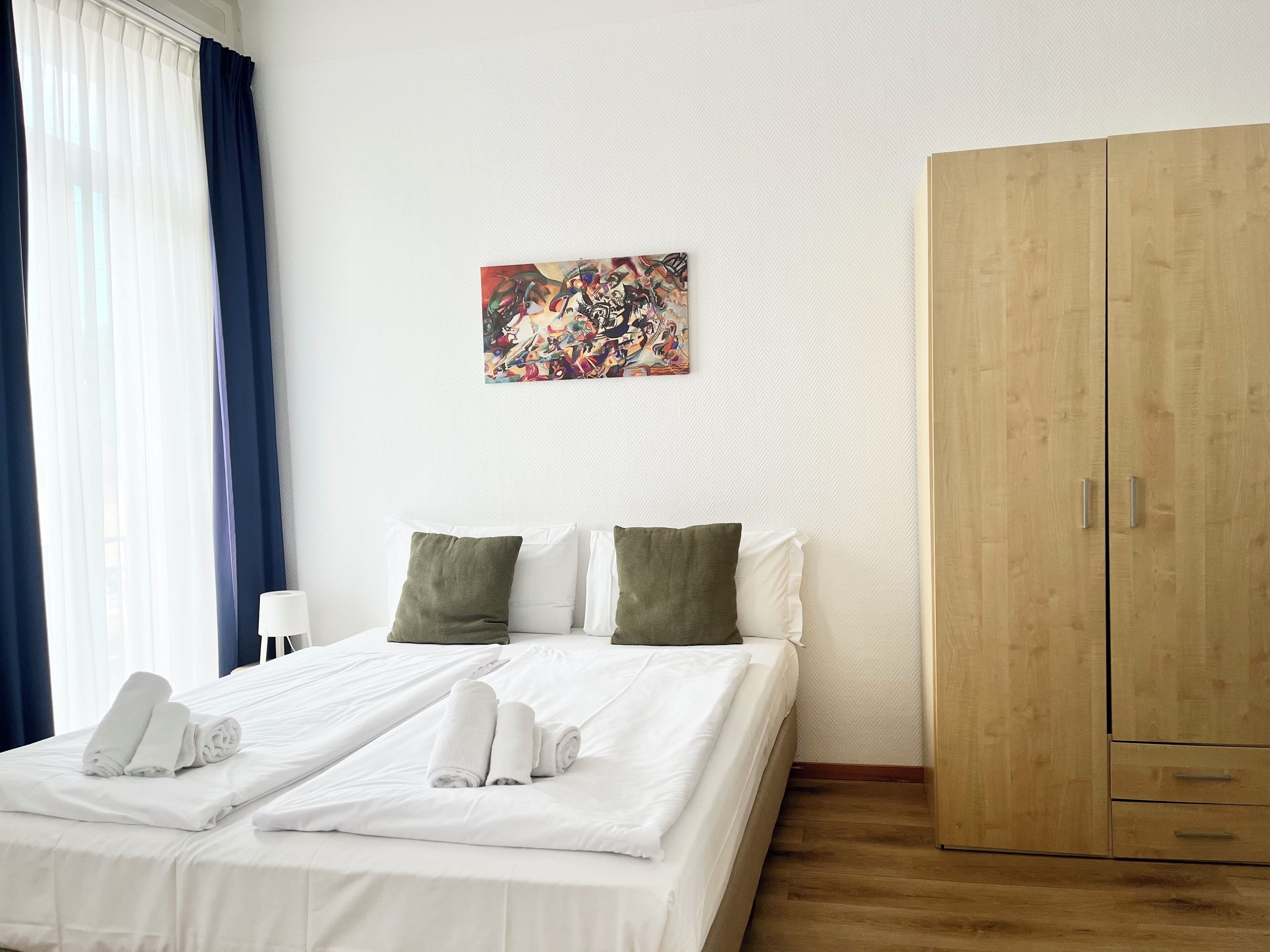 Habitación de hotel con cama, armario y un cuadro en la pared.