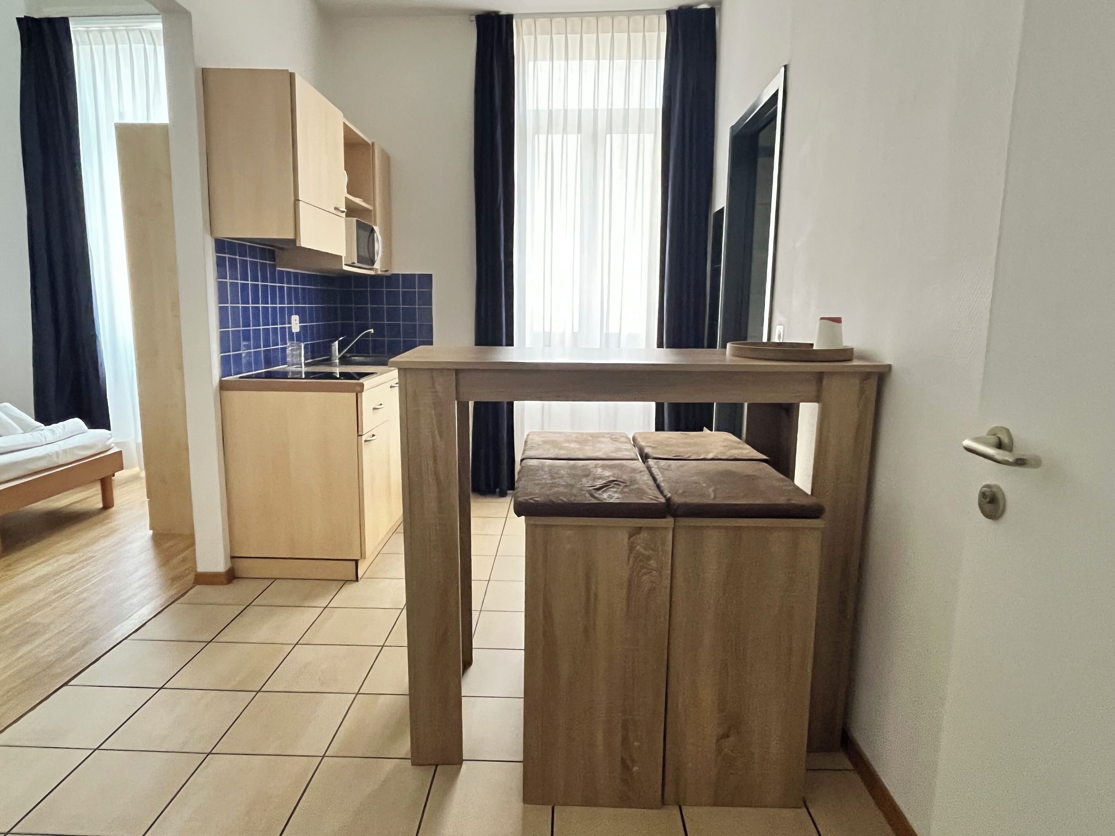 A compact kitchen with a wooden table and bench, a microwave, and a sink.