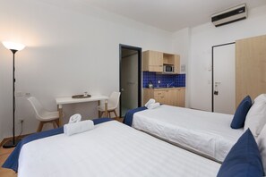 A hotel room with two beds, a desk, a chair, a microwave, and a small kitchenette. - Lugano Center GuestHouse (Lugano)
