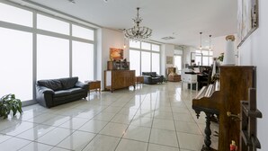 A spacious living room with a piano, a chandelier, and large windows. - Lugano Center GuestHouse (Lugano)