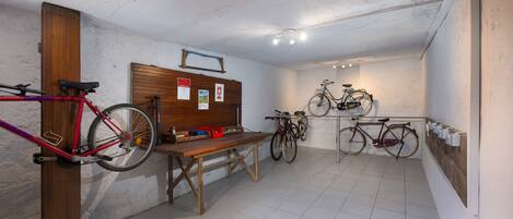 A room with bicycles, a wooden table, and a bulletin board.