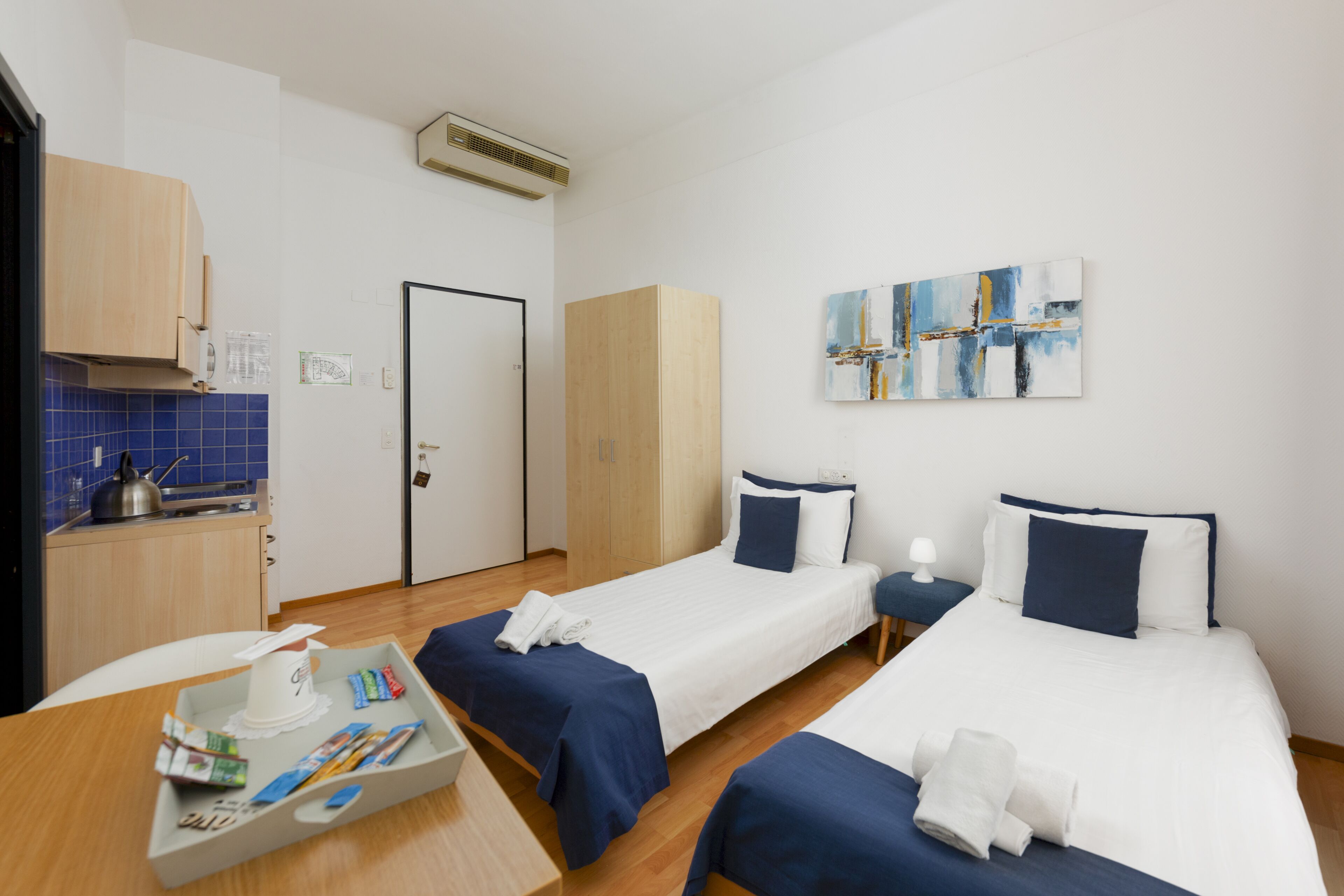 Ein Hotelzimmer mit zwei Betten, einer Küchenzeile und einem Bild an der Wand.