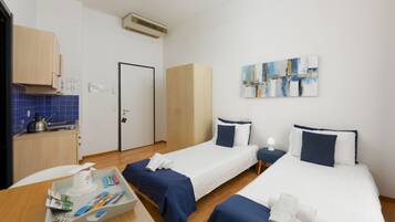 Ein Hotelzimmer mit zwei Betten, einer Küchenzeile und einem Bild an der Wand.