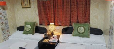 Ein Hotelzimmer mit zwei Betten, einem Nachttisch mit Lampe und einem kleinen Tisch mit Fernbedienung.