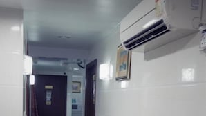 A hallway with a black marble floor, white walls, and an air conditioning unit mounted on the wall. - Mabuhay Hotel (Kowloon)
