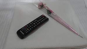 A remote control and a pink pen on a white towel. - Mabuhay Hotel (Kowloon)