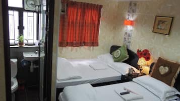 Quarto de hotel com duas camas, banheiro e janela com cortinas.