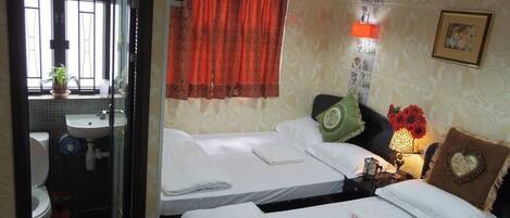 A hotel room with two beds, a bathroom, and a window with curtains.